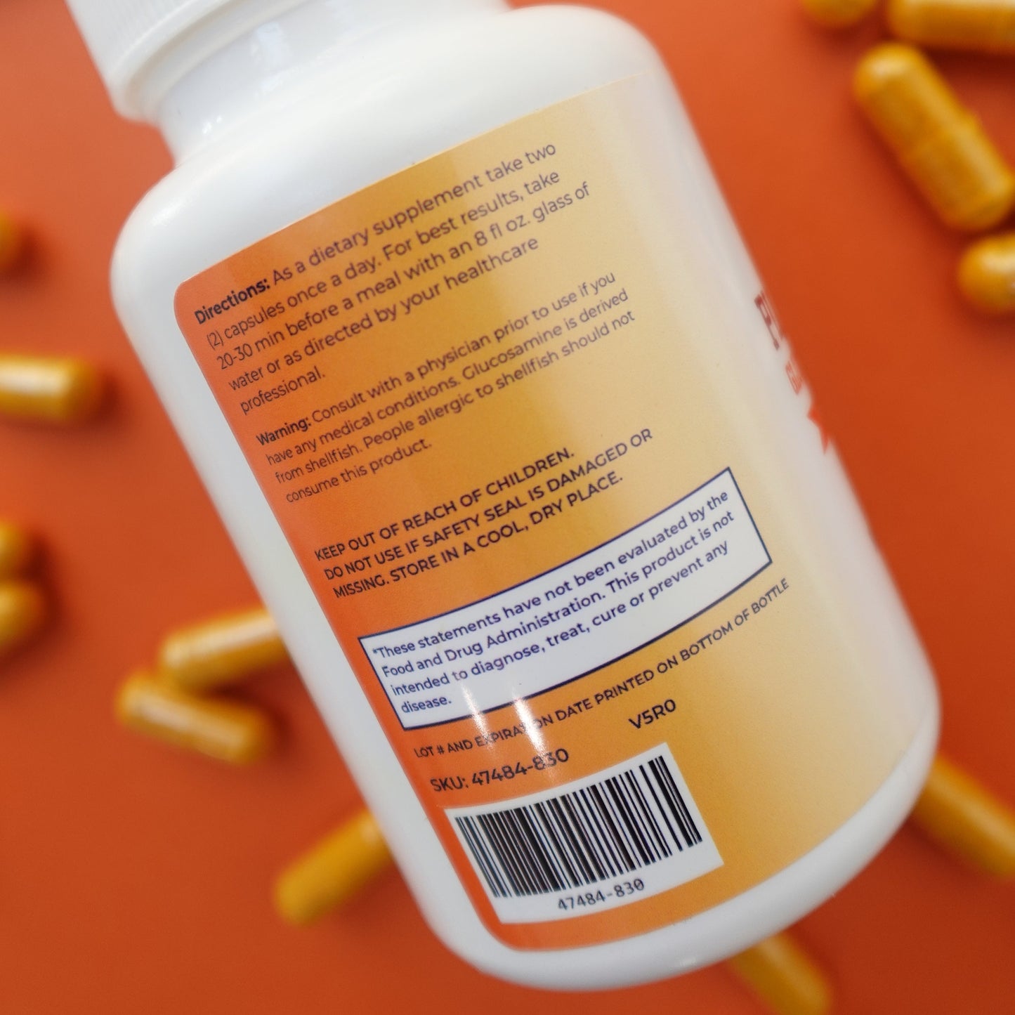 Supplement bottle with label and pills on an orange background