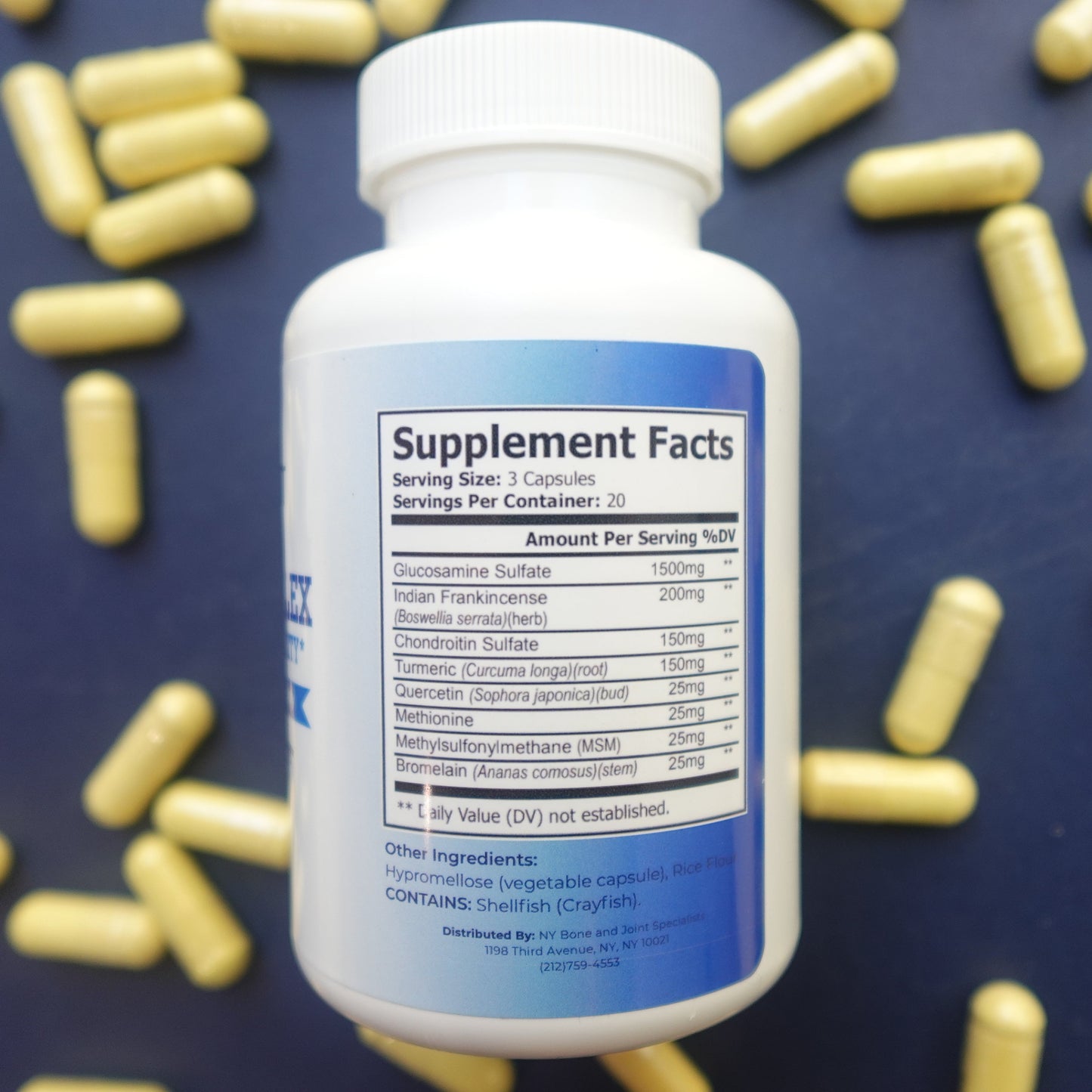Supplement bottle with blue label on a dark background with scattered capsules