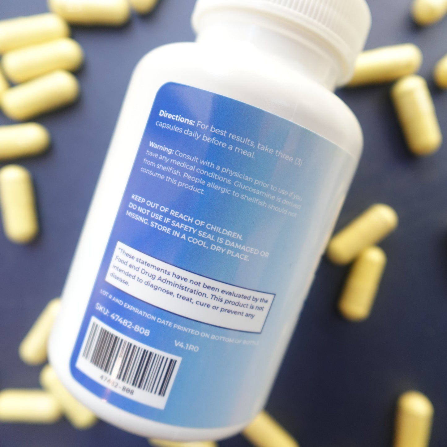 Medication bottle with blue label on a dark surface with scattered capsules