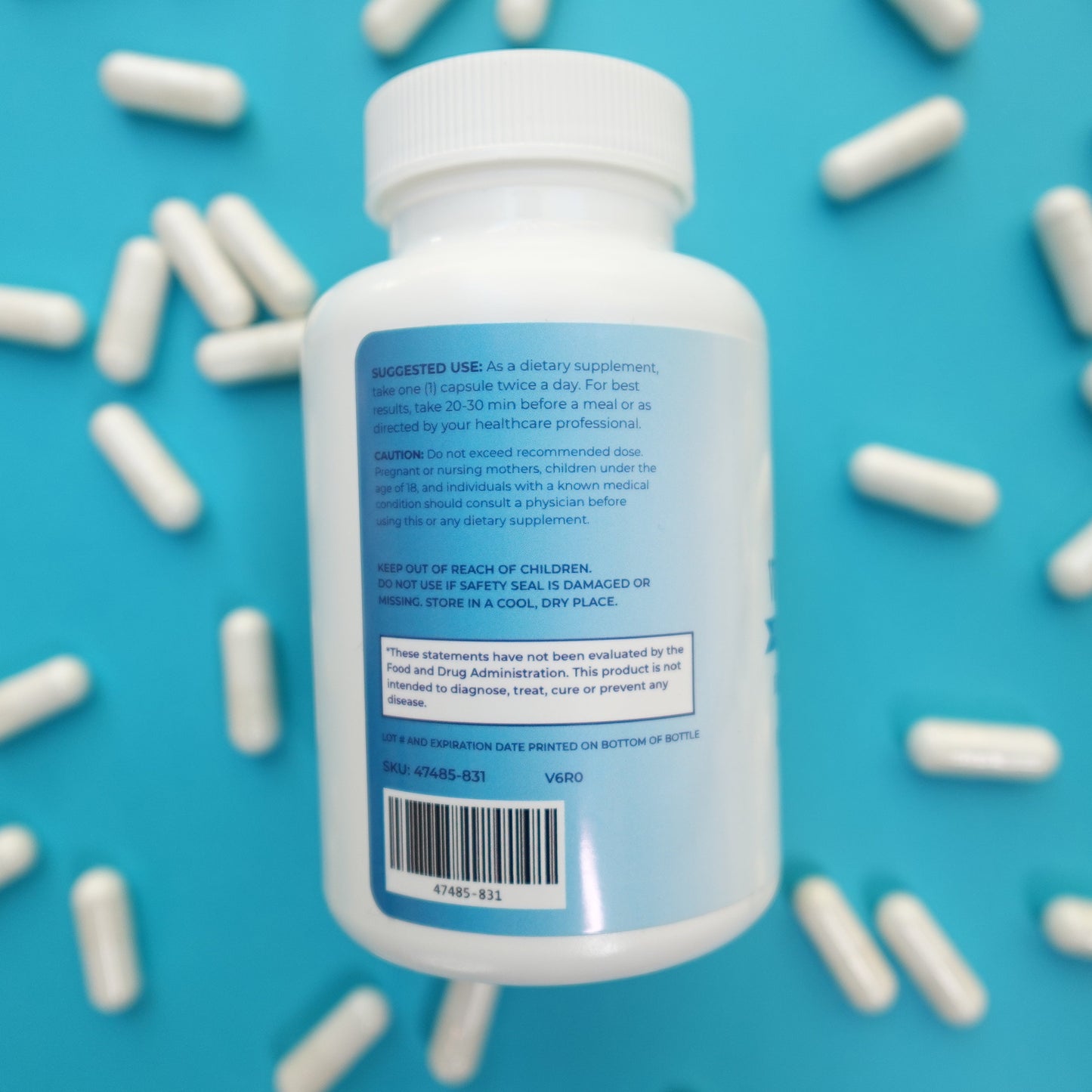 Bottle of supplements with a blue label on a blue background with scattered white capsules.