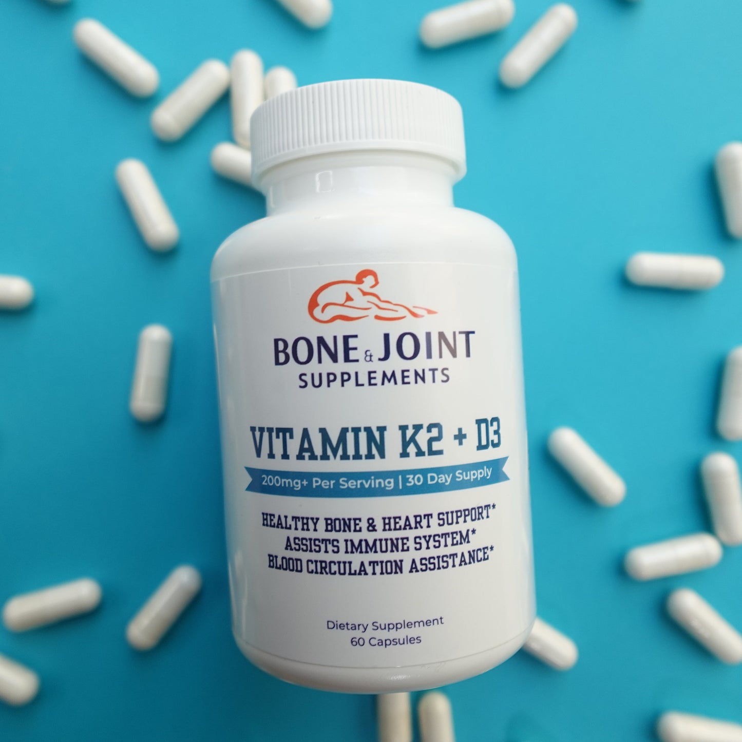Bottle of Bone & Joint Supplements Vitamin K2 + D3 on a blue background with scattered capsules.